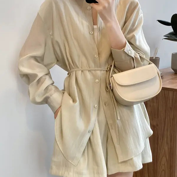 Beige button-up romper with long sleeves and cinched waist for breathable sun protection