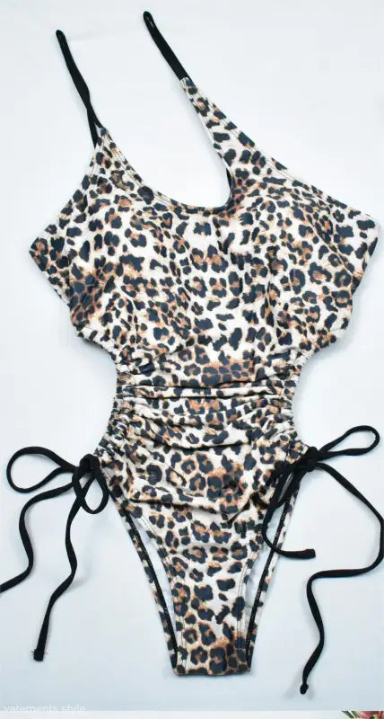 Leopard print one-piece bikini with black straps and side ties, perfect for boho beach style