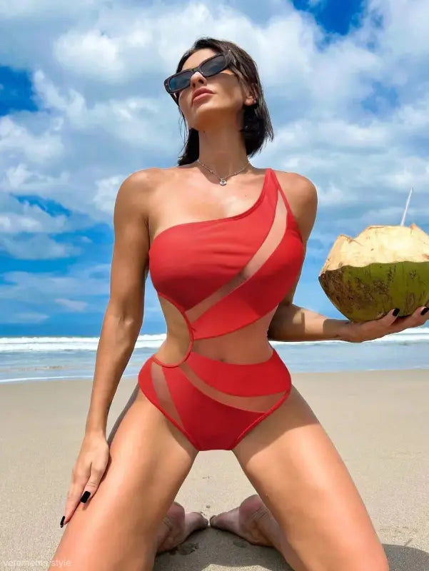 Woman in a red boho color block cutout piece swimsuit holding a coconut drink with free shipping