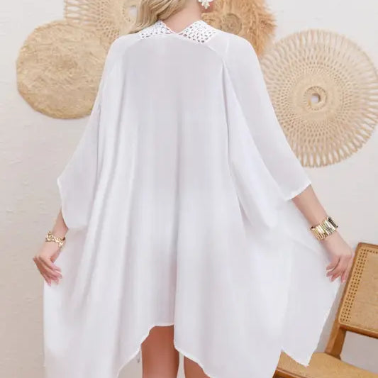 Blonde woman wearing flowing white kaftan-style sun protection jacket with embellished collar