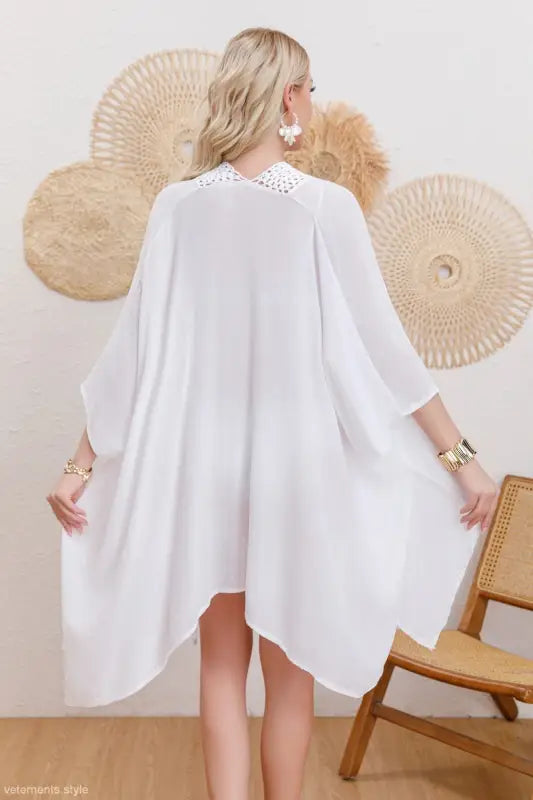 Blonde woman wearing flowing white kaftan-style sun protection jacket with embellished collar