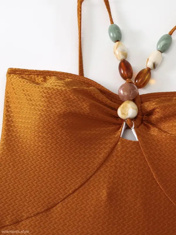 Textured brown top with beaded straps featured on a wine red jumpsuit