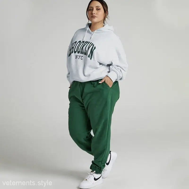 Woman modeling a Brooklyn Sweatshirt Set featuring a white hoodie and green sweatpants