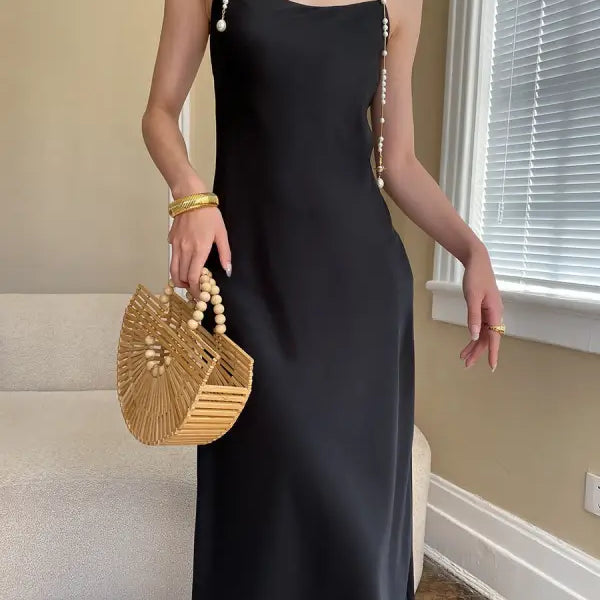 Budding green satin glossy cami dress with pearl necklaces and woven handbag
