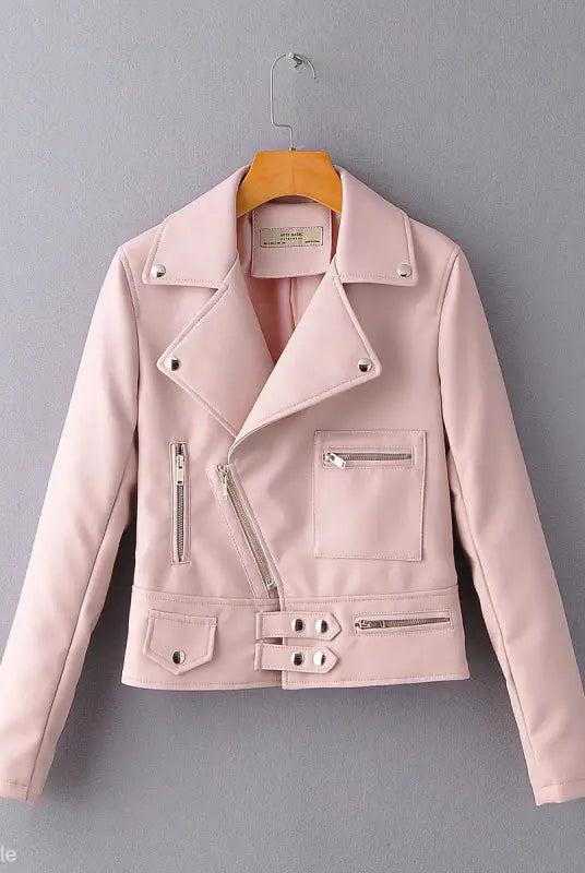 Pale pink faux leather biker jacket hanging on a wooden hanger for fall/winter style