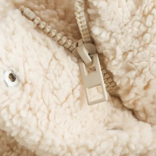 Close-up of zipper on plush cream-colored fleece cotton jacket for fall winter outerwear