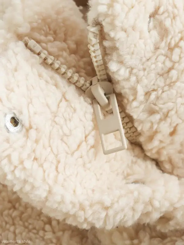 Close-up of zipper on plush cream-colored fleece cotton jacket for fall winter outerwear