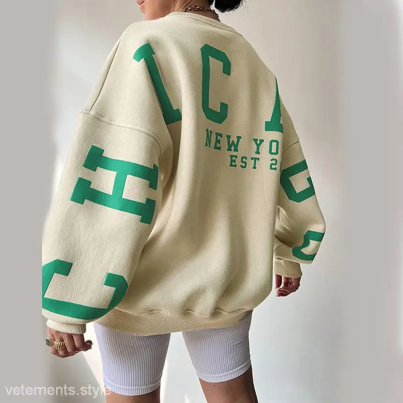 Oversized cream sweatshirt featuring green lettering in a knitted graphic printed style