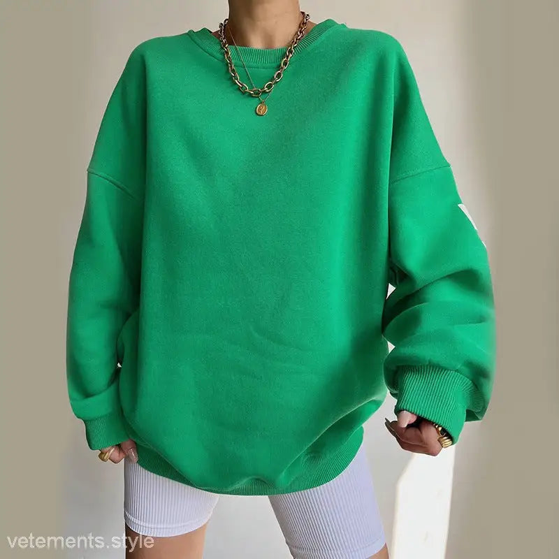 Oversized green knitted graphic printed hoodie styled with gold necklaces for casual wear