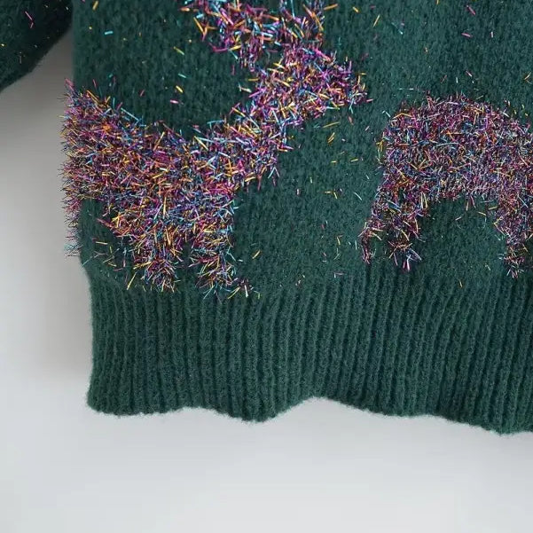 Green knit deer holiday sweater with colorful tinsel decorations for festive occasions