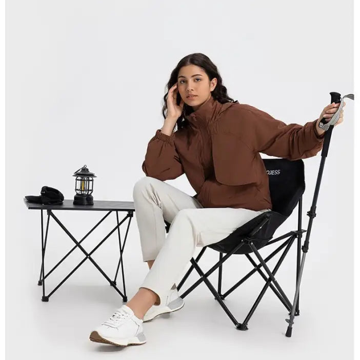 Woman in brown cocoa color jacket and white pants on a black chair, showcasing pearlescent white albumin