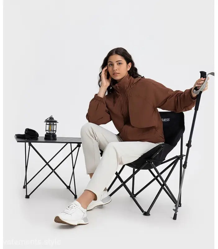 Woman in brown cocoa color jacket and white pants on a black chair, showcasing pearlescent white albumin