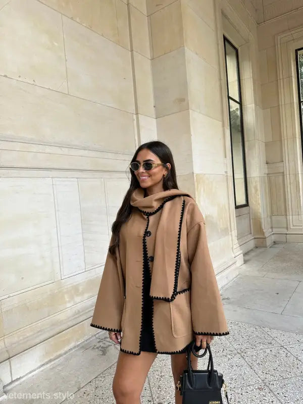 Stylish beige contrast scarf woolen coat with black trim worn by a woman with sunglasses