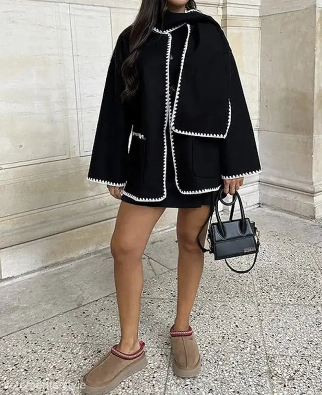 Black cape-style coat with white trim and contrast scarf woolen detail for fall winter fashion