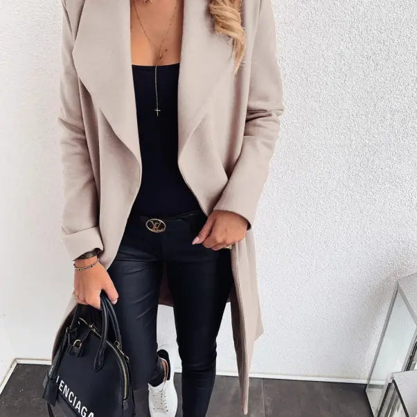 Beige open-front trench coat over black top and pants with white sneakers for fall style