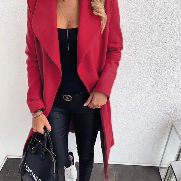 Vibrant red trench coat over black outfit with white sneakers and designer handbag
