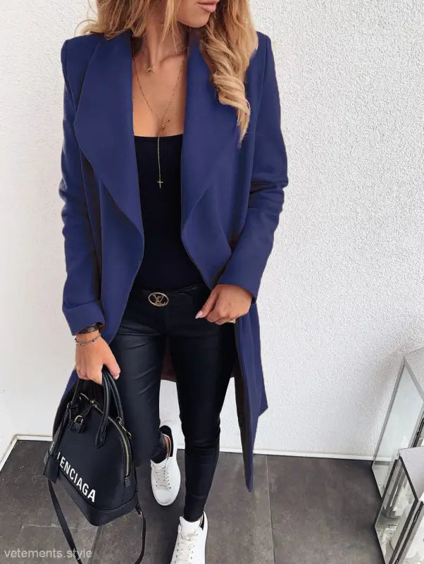 Navy blue trench coat over black outfit featuring white sneakers and Balenciaga handbag