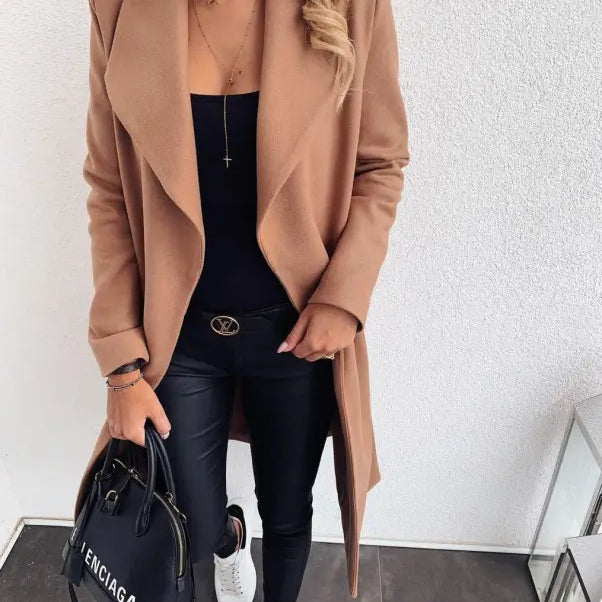Camel-colored trench coat over black outfit with sneakers and Balenciaga handbag
