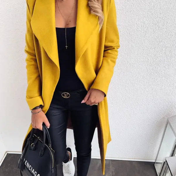Bright yellow trench coat over black outfit with white sneakers for fall and winter
