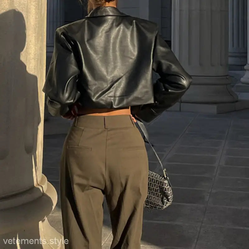 Black leather cropped motorcycle jacket paired with high-waisted tan trousers, stylish and versatile