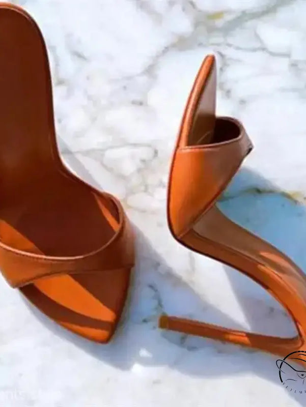 Pair of orange high-heeled chic summer slide stiletto pumps with pointed toes