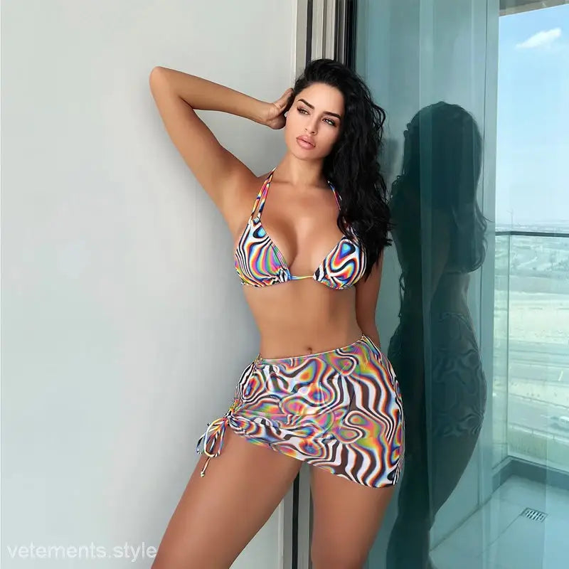 Woman in colorful three piece bikini set with boho swirl print and sheer mini skirt