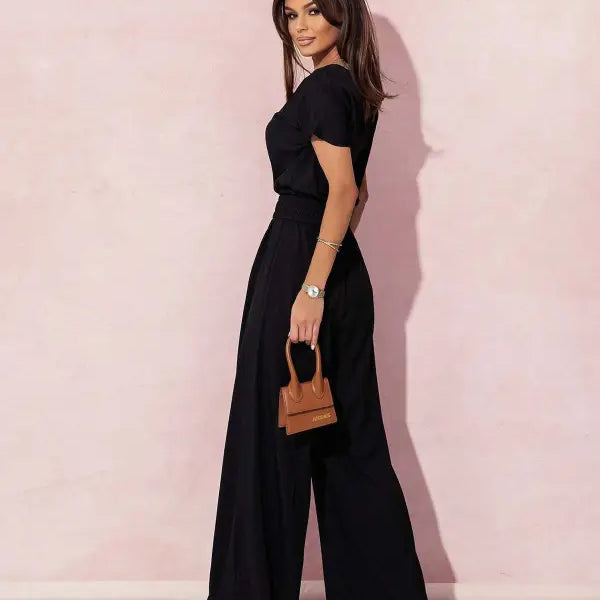 Woman in black wide-leg casual trousers jumpsuit holding a brown handbag