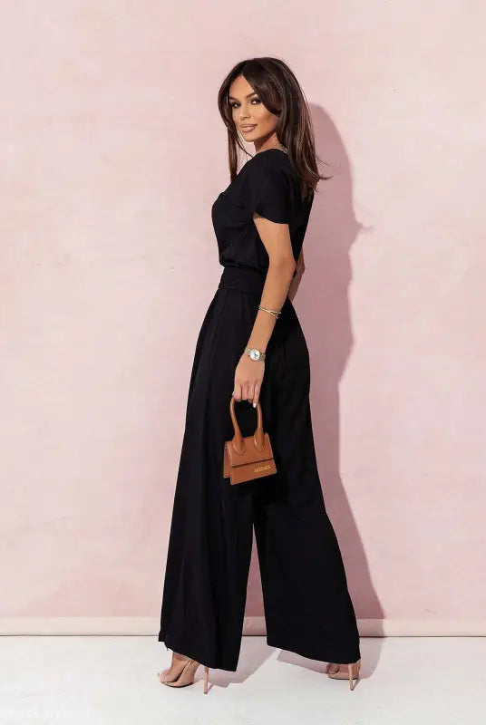 Woman in black wide-leg casual trousers jumpsuit holding a brown handbag