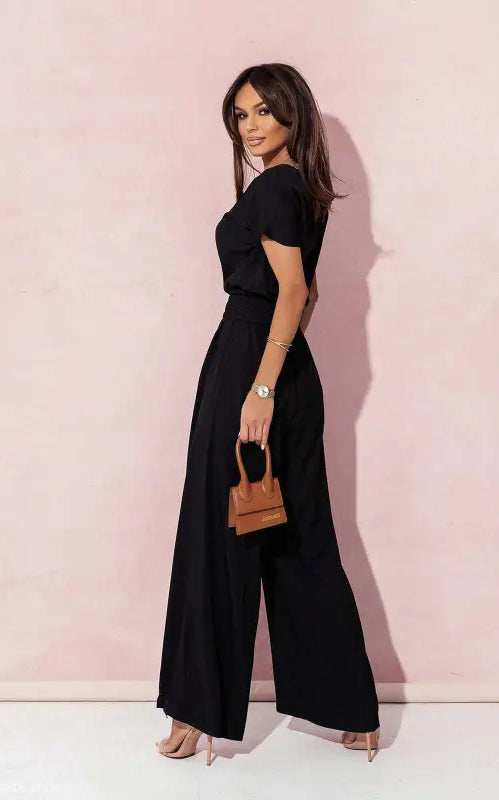 Woman in black wide-leg casual trousers jumpsuit holding a brown handbag