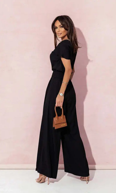 Woman in black wide-leg casual trousers jumpsuit holding a brown handbag