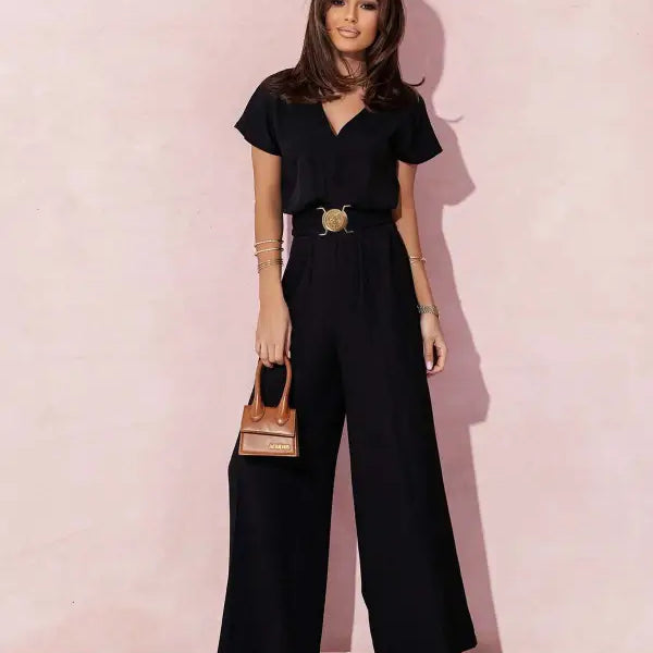 Woman wearing a black wide-leg casual trousers jumpsuit with gold belt and handbag