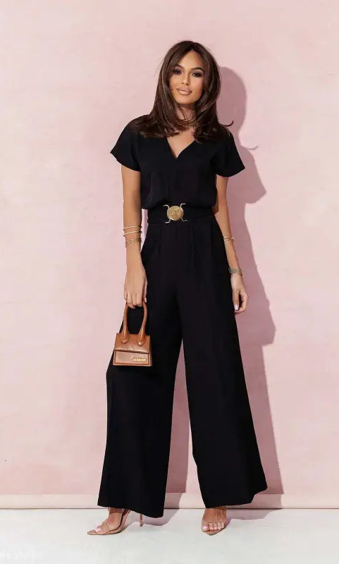 Woman wearing a black wide-leg casual trousers jumpsuit with gold belt and handbag