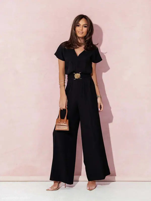 Woman wearing a black wide-leg casual trousers jumpsuit with gold belt and handbag