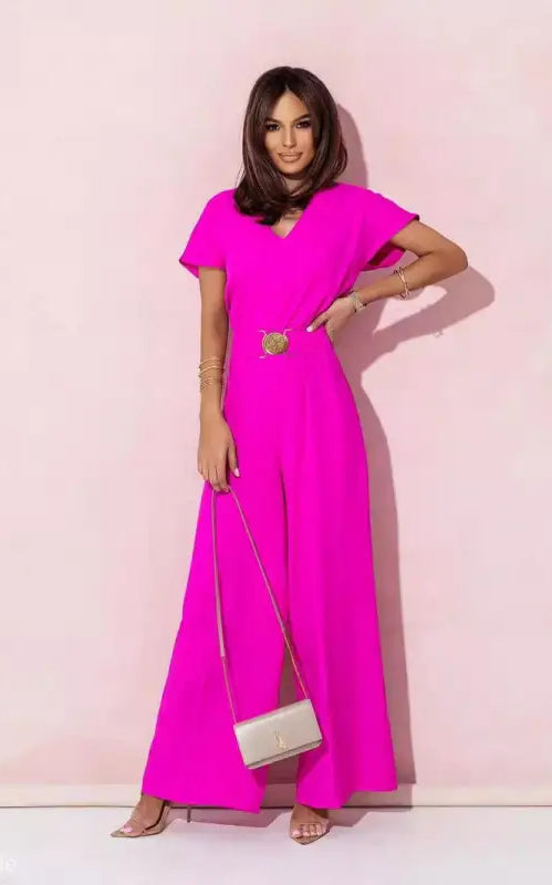 Woman wearing a vibrant coral red casual trousers jumpsuit with gold belt and clutch purse