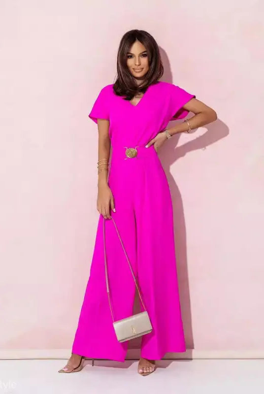 Woman in coral red casual trousers jumpsuit with short sleeves, gold belt, and clutch purse