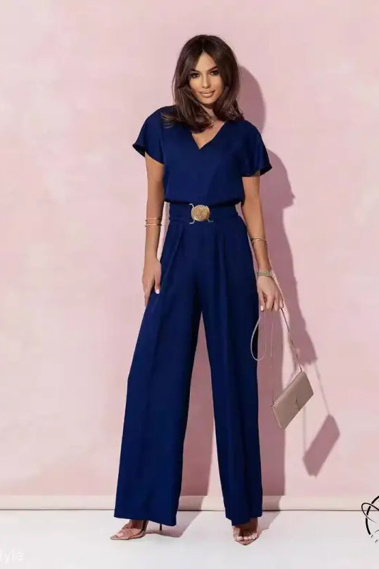 Woman in navy blue casual trousers jumpsuit with belt and light handbag