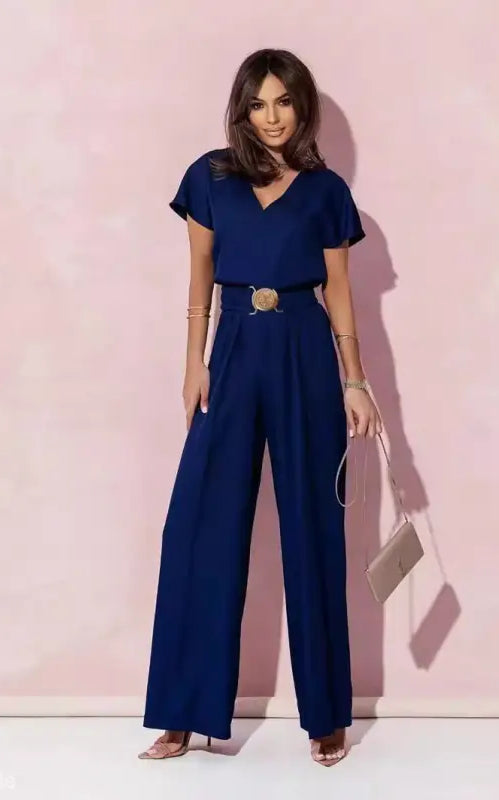 Woman in navy blue casual trousers jumpsuit with belt and light handbag