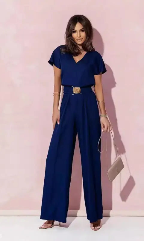 Woman in navy blue casual trousers jumpsuit with belt and light handbag