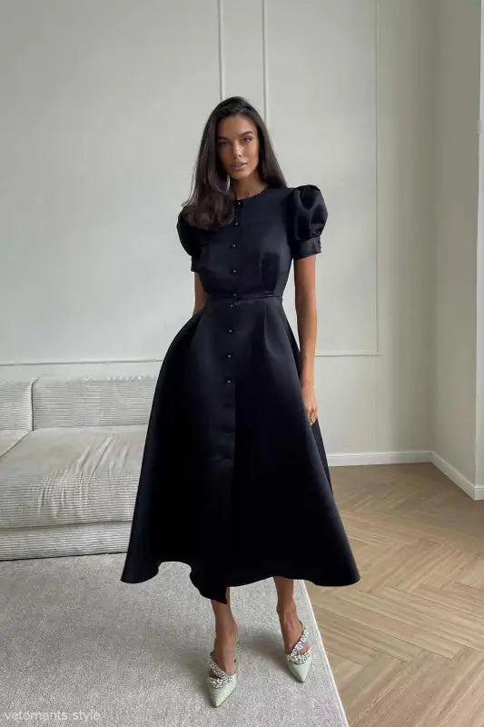 Elegant woman in a black midi swing line dress with puff sleeves and sparkly shoes
