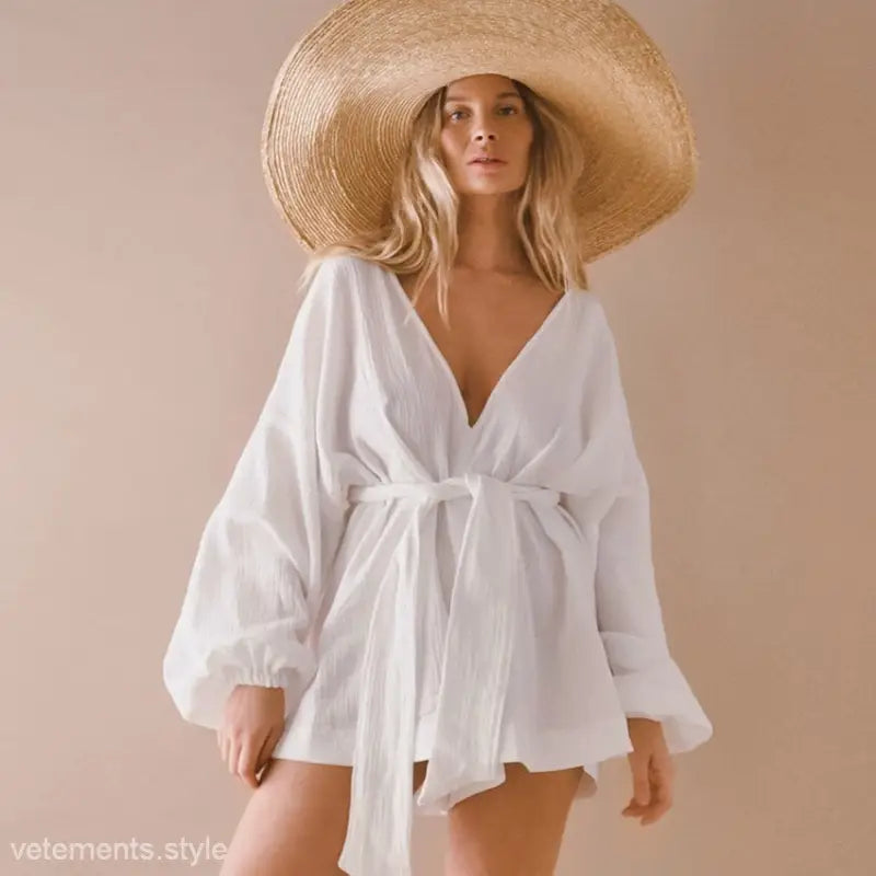 Woman wearing a wide-brimmed straw hat and white waist tight cotton jumpsuit for comfortable lounging