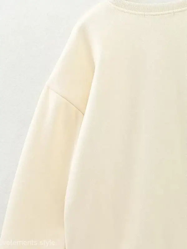 Cream-colored cute pattern sweater featuring a round neckline and dropped shoulder seam