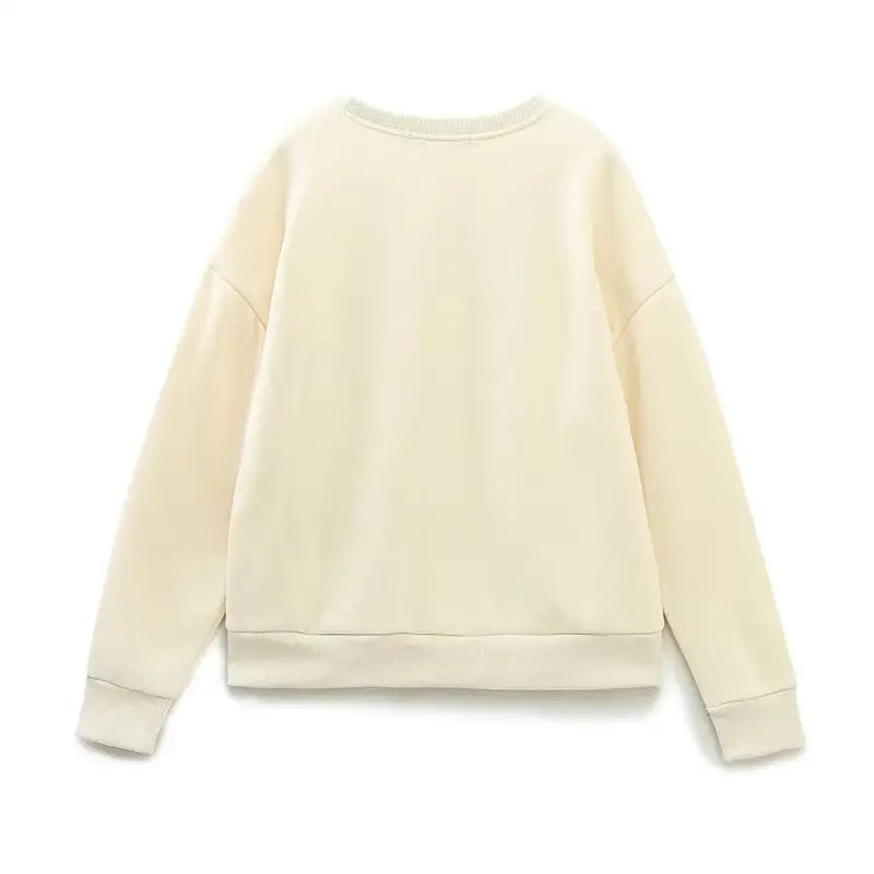 Cream-colored crewneck sweatshirt with ribbed cuffs, perfect for a cute pattern sweater