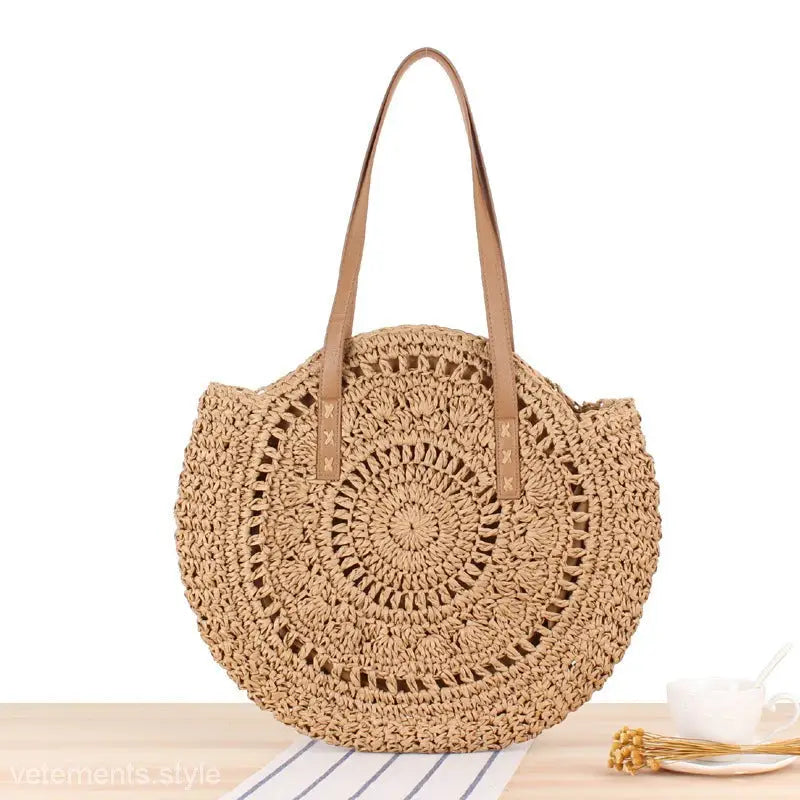 Circular woven straw handbag with tan leather handles for a large striped blue cross bohemian bag