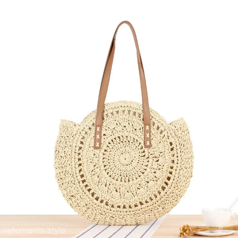Circular cream-colored crocheted straw bag with brown leather handles for a large striped blue cross bohemian bag