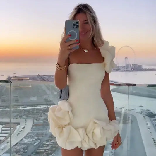 Woman in white floral summer dress with ruffled asymmetrical design and one shoulder sleeve