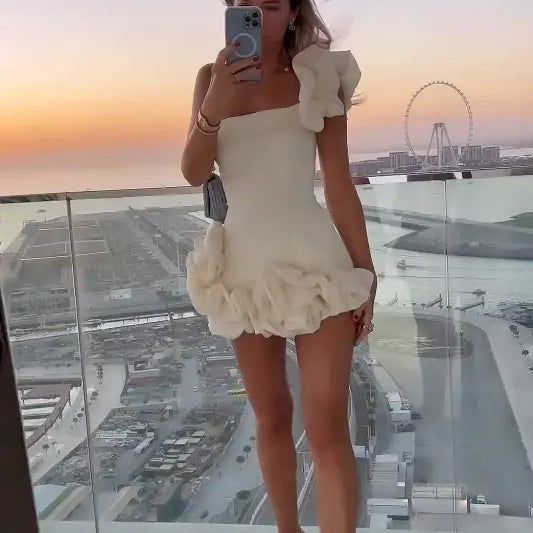 Woman in a white ruffled summer dress with an asymmetric design and one shoulder sleeve