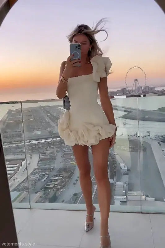 Woman in a white ruffled summer dress with an asymmetric design and one shoulder sleeve