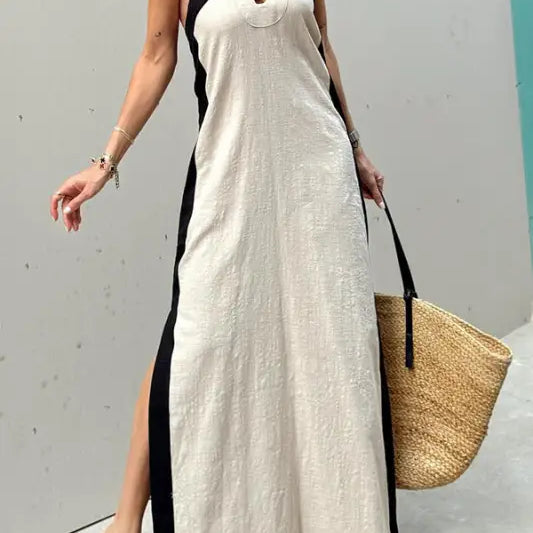Long white halter-neck maxi dress with black trim and side slits.