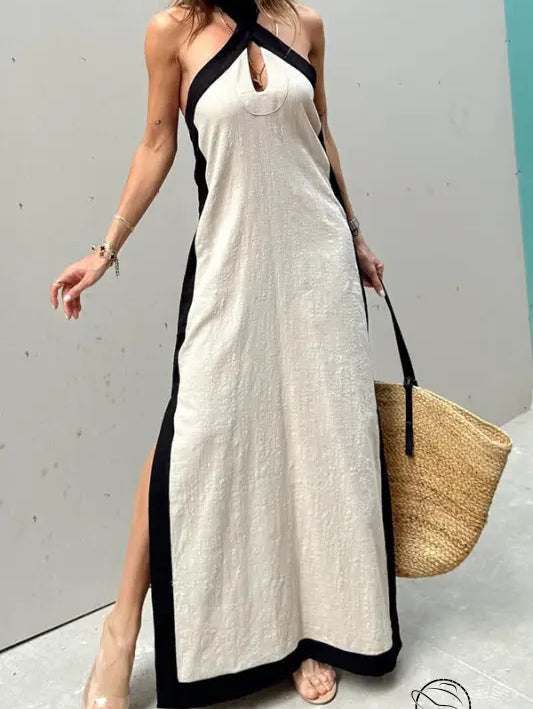 Long white halter-neck maxi dress with black trim and side slits.