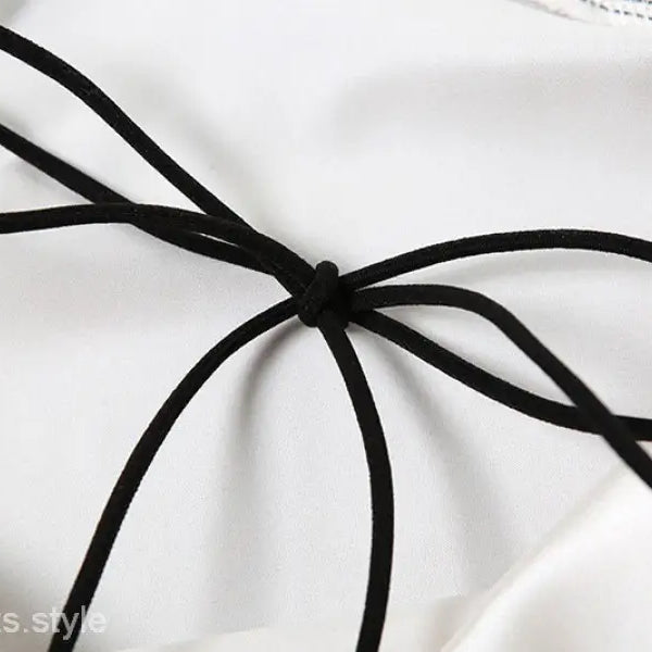 Black cord tie accentuating the elegant backless lace split dress on white fabric